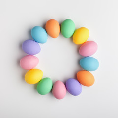 Creative layout made of colorful eggs painted in pastel colors on white background. Flat lay. Easter concept.