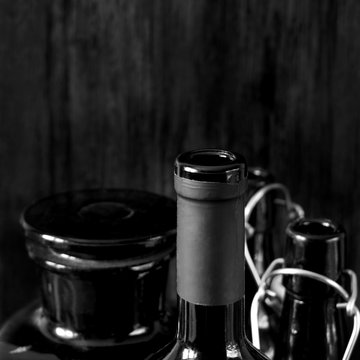 Different dark glass bottles for alcoholic drinks on black wooden background. Black and white photo