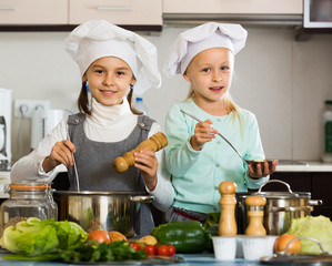 Two girls preparing vegetables and smiling indoors