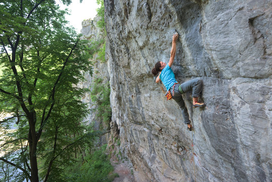 Woman rock climbing on steep craggy wall using climbing gear