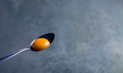 Raw egg yolk on a metal spoon