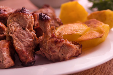 Mutton shish kebabs with baked potato on the plate close up