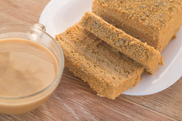 Traditional Russian baked honey cake, sliced on white plate and glass cup with coffee cocoa drink