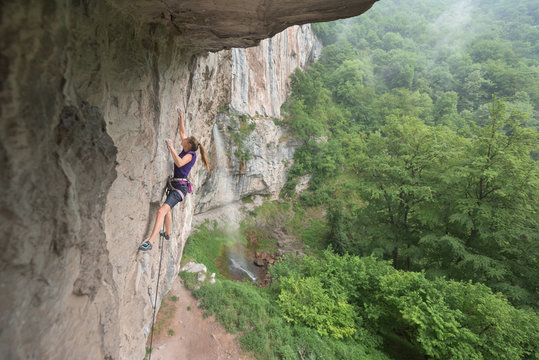 Side view of female rock climber ascending on rock wall