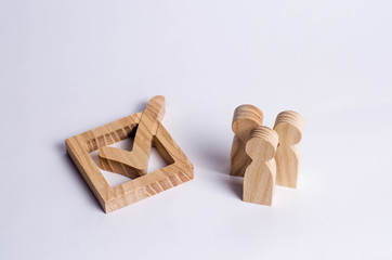 Three wooden human figures stand together next to a tick in the box. The concept of elections and social technologies. Volunteers, parties, candidates, constituency electorates. Human rights.