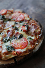 Pizza bacon ham tomato and cheese on top on wood background vintage style