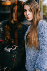 Blue eyed amazing young girl self reflection portrait. Beautiful babe with sensual lovely face reflected in shop abstract showcase. Unusual strange hipster woman expressive facials. Alter ego concept