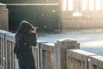 Young woman taking pictures on historical bridge in Rome while snowing in winter blurred background focus on snowflakes