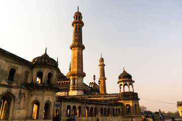 Fototapeta na wymiar The entrance and gardens of the bara imambara. The spires and dome of the main building and the beautiful well maintained grounds make this a famous tourist spot. Shot during the golden light of