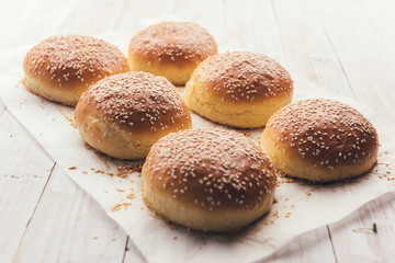 Homemade burger bun on bakery parchment on wooden table. Food photography