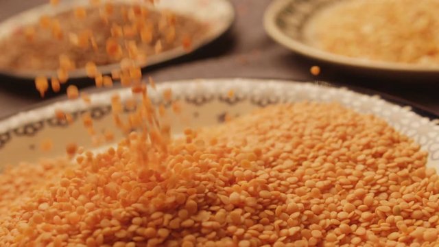 Red lentils are strewed on a plate close up
