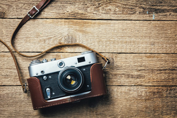 Old vintage film photo camera with brown leather strap on grunge wooden table. Photographe concept background - Powered by Adobe