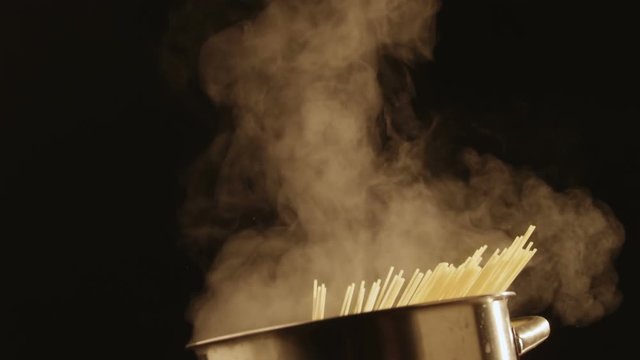 Throws spaghetti in a boiling pan