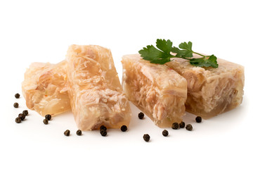 Meat jelly cut in slices with the parsley leaves and black pepper on a white, closeup.