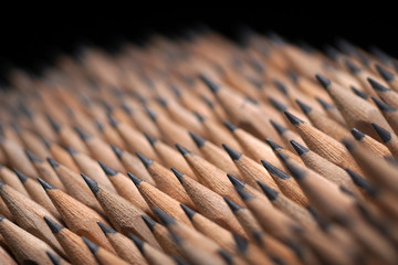 Bunch of identical graphite pencils on black background