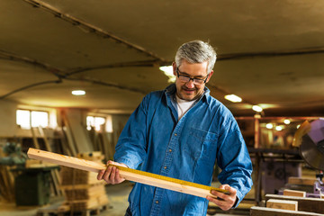 middle aged carpenter checking measures in his workshop