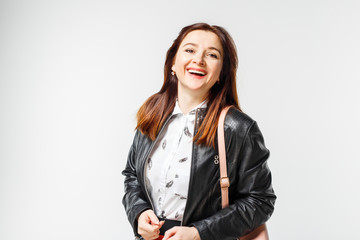 Young smiling woman in leather jacket in studio. Happy woman with long beautiful hair on gray background