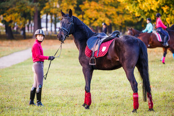 Group of rider girls walking with horses in park. Equestrian recreation activities background with copy space