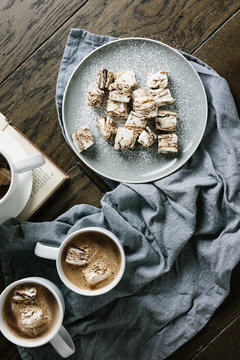 Plate of homemade marshmallows with two mugs hot chocolate
