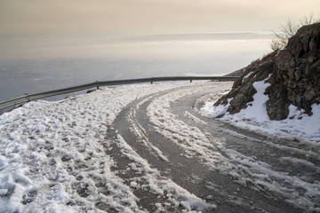 Mountain road in winter, curve with metal crash barrier
