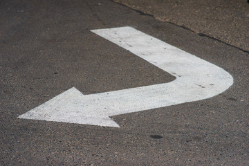 Painted white paint on the asphalt sign arrow indicating the direction of movement for cars while...