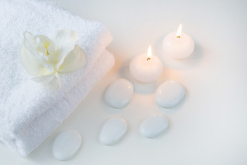 White objects on the white table: towels, stones and candles