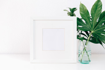 Minimalism mockup white frame with green leaves in vase .  Home decor, Styled still life