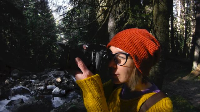 An active healthy hipster girl-photographer with a camera in her hands walks through the forest. The girl is taking pictures. Low key 60 FPS slow motion. GoPro 6 Black with a three-axis antimicrobial