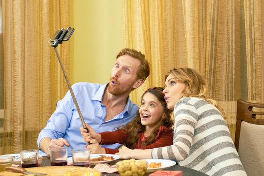 Family taking a funny selfie. Parents with daughter, dinner.