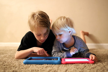 Big Brother Showing Little Sister How to PLay a Game on Tablet
