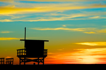 Silhouette of a lifeguard stand against a colorful sunset