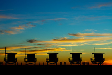 Silhouette of five lifeguard stands at the beach during a colorful sunset