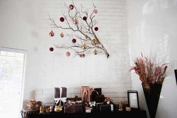 Gifts wrapped in black and copper wrapping paper under a branch with decorative balls