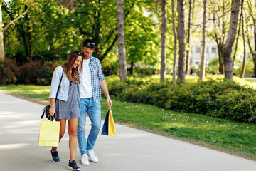 Fototapeta premium Happy young couple walking through the park after shopping