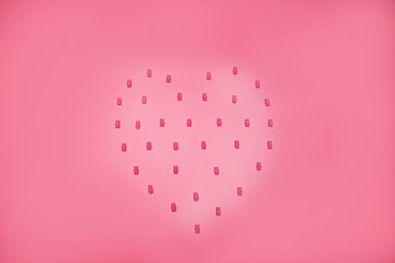 Pink gummy bears form a heart against a pink background