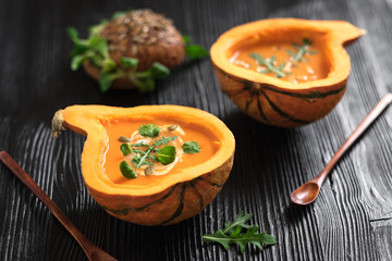Half pumpkin with soup on black background. Horizontal composition. Greens and veggies