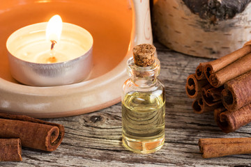 A bottle of cinnamon essential oil with cinnamon and an aroma lamp