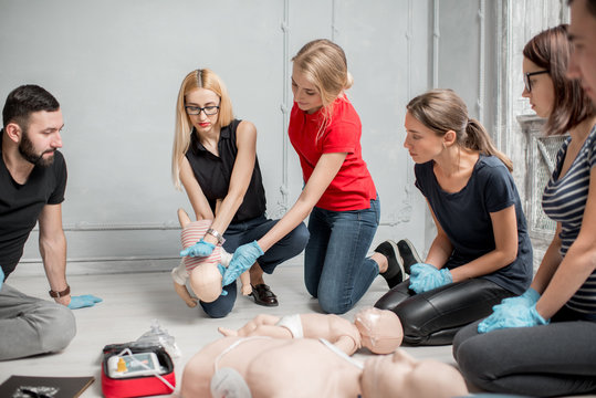 People learning how to safe a life when the baby is choked sitting together with instructor during the first aid training indoors