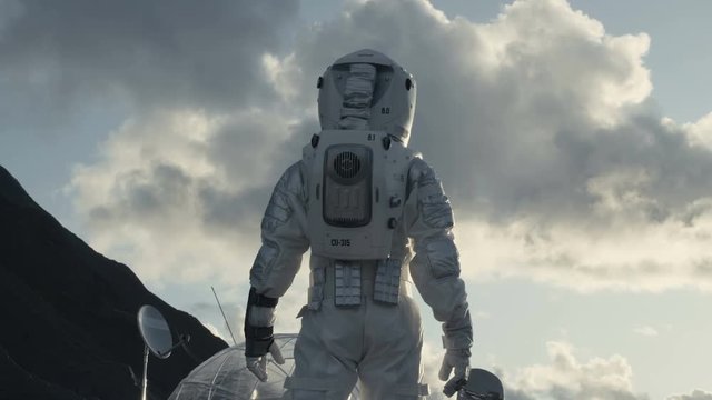 Following Shot of the Astronaut Looking Around on Frozen Alien Planet. In the Background His Base/ Research Station. Shot on RED EPIC-W 8K Helium Cinema Camera.
