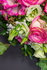 Close up view of a bunch or a bouquet of pink roses, pink Alstroemeria and white Lisianthus flowers  on a gray background with copy space