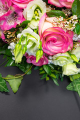 Close up view of a bunch or a bouquet of pink roses, pink Alstroemeria and white Lisianthus flowers  on a gray background with copy space