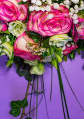 Close up view of a bunch or a bouquet of pink roses, pink Alstroemeria and white Lisianthus flowers  on a purple background with copy space