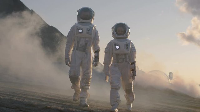 Two Astronauts in Space Suits Confidently Walking on Alien Planet, Exploration Expedition on the Planet's Surface that is Covered with Rocks, Gas and Smoke. Shot on RED EPIC-W 8K Helium Cinema Camera.