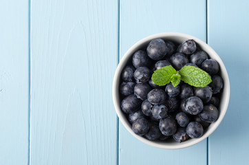 Bowl of Blueberries from Above on Painted Blue Wood Plank Table with Mint Leaves