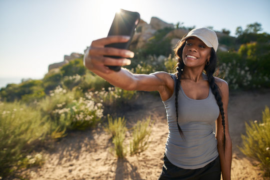 fit female african american hiker taking a selfie on smartphone while out on hike