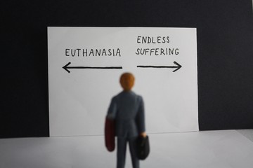 Euthanasia versus endless suffering concept with miniature man and arrows. Legalization of assisted suicice for some patients theme dillema. - obrazy, fototapety, plakaty