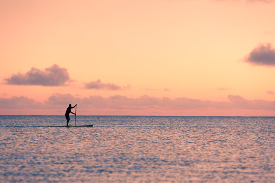 Beach life and active lifestyle concept. Stand up paddle border padding across the sea. 