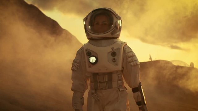 Following Shot of Female Astronaut in Space Suit Confidently Walking on Mars, Turing Around and Looking into the Camera. Shot on RED EPIC-W 8K Helium Cinema Camera.