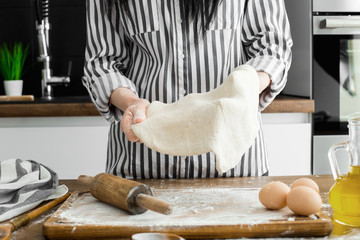 Female hands making dough on kitchen background