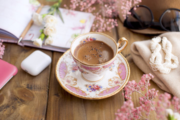 Morning coffee in a cozy cafe. Planning the day in notepad. Decor of pink flowers. Free space for text. Card.